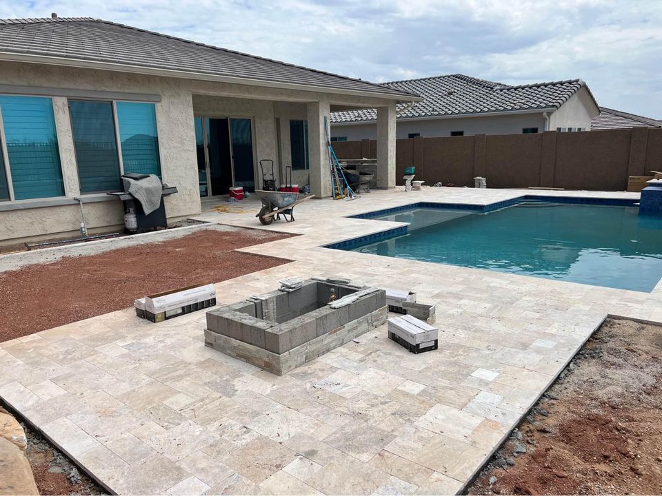 The backyard view reveals a house under construction, featuring a partially built swimming pool and a fire pit nestled on the emerging brick patio. Building materials are scattered about, with a ladder leaning against the house, while Santa Fe masonry experts bring craftsmanship even as the sky remains overcast.