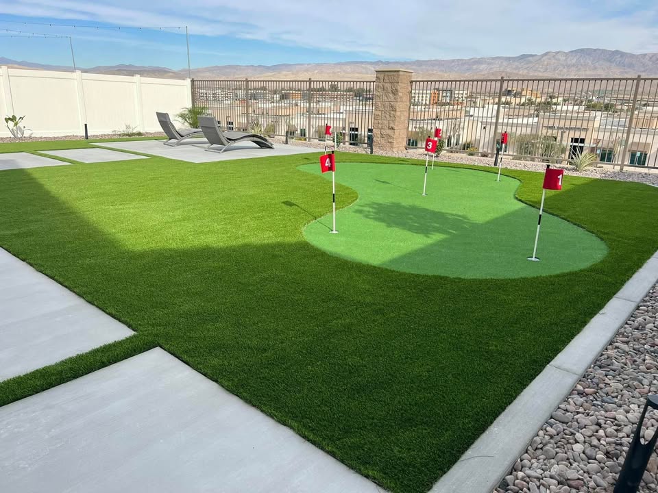 artificial grass lawn and putting green in a backyard in Albuquerque NM. Putting green has 6 holes, each with a small red flag to mark the hole